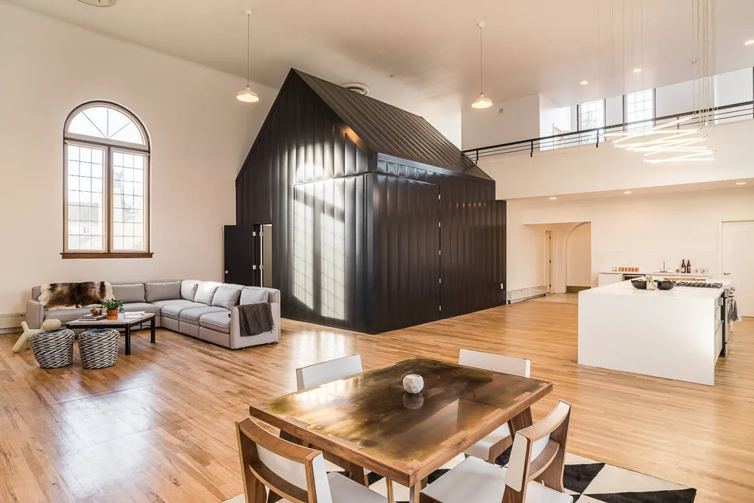 The matte black tiny house standing inside the white church nave